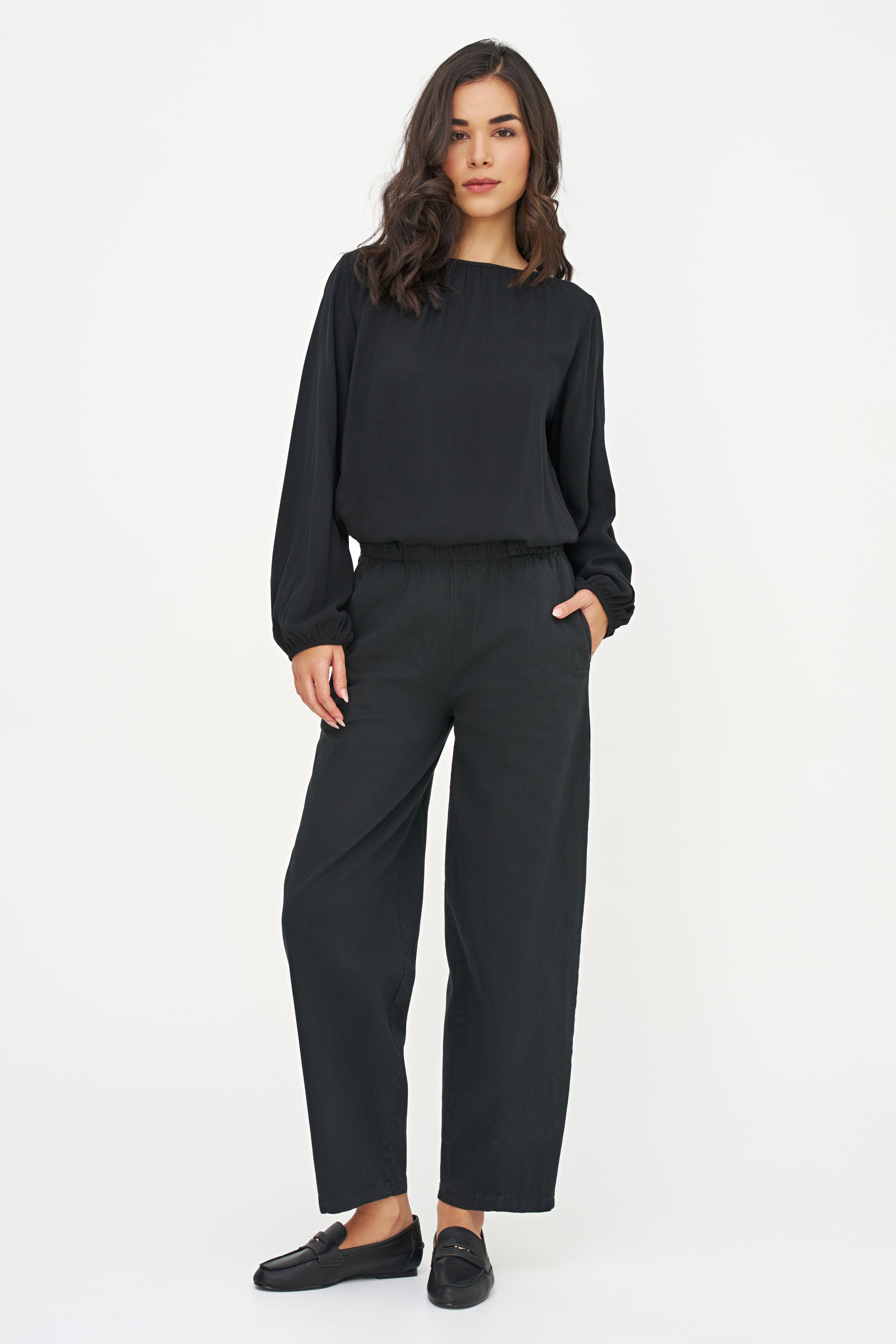Blouse noire à manches bouffantes portée avec un pantalon noir, vue plein pied
