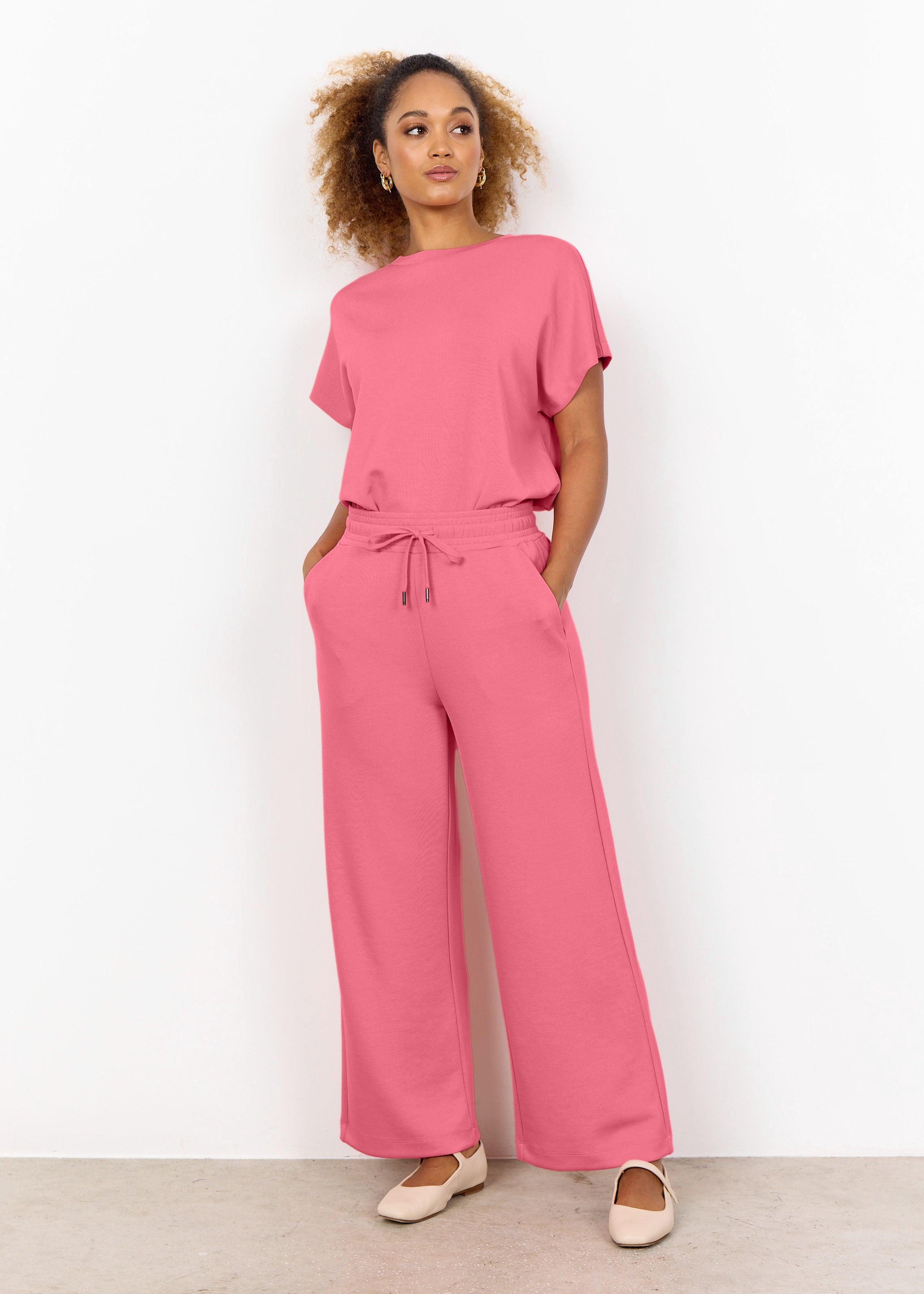 Pantalon large couleur rose, tissu doux et extensible en modal, polyester et élasthanne, coupe fluide et confortable.