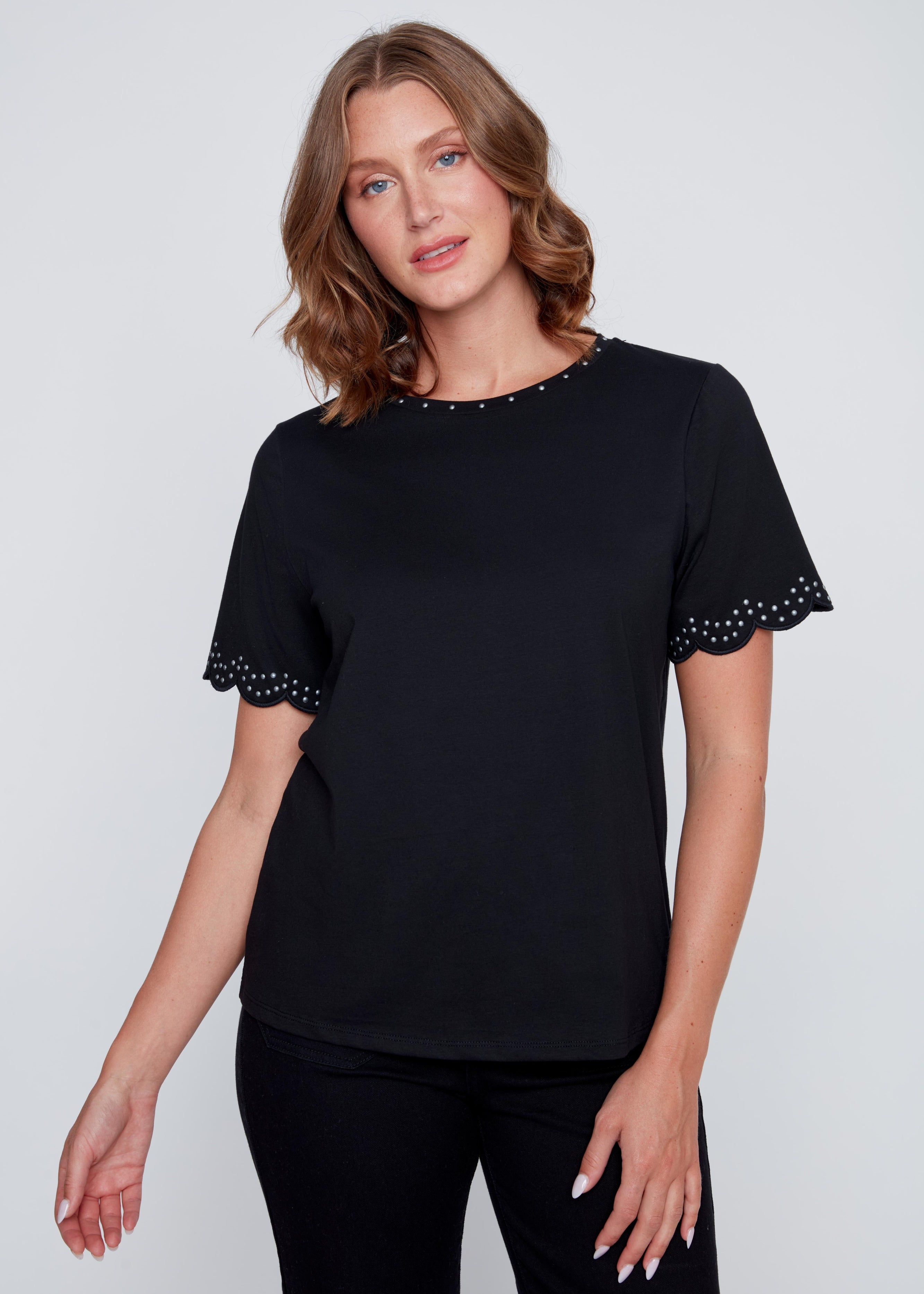 T-shirt col rond avec studs argentés au col et aux manches, finition arrondie féminine aux manches, offert en ivoire et en noir.