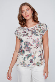 T-shirt écru à col rond avec imprimé tropical rose et vert, boutons décoratifs en bois au bas du chandail près des hanches.