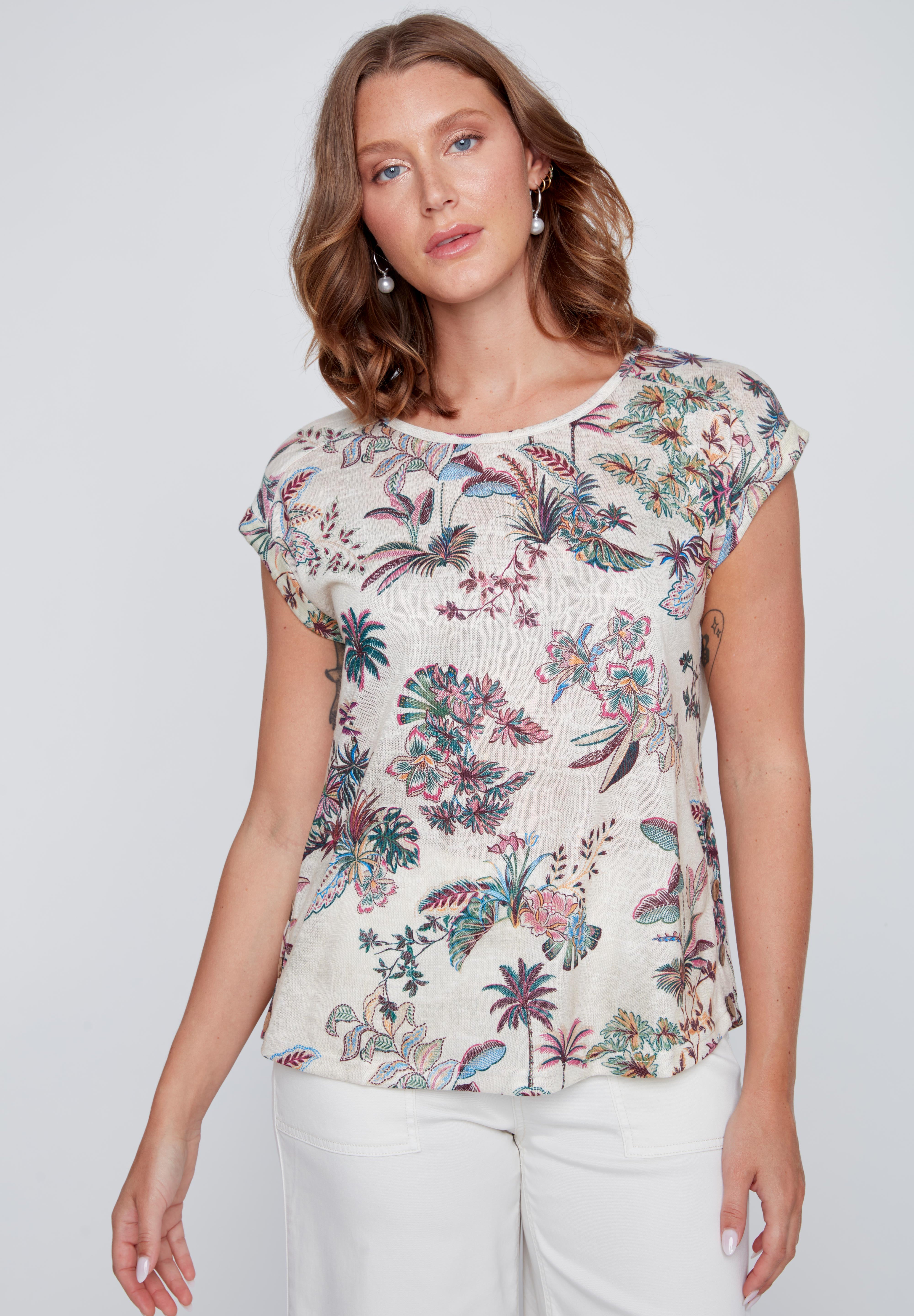 T-shirt écru à col rond avec imprimé tropical rose et vert, boutons décoratifs en bois au bas du chandail près des hanches.