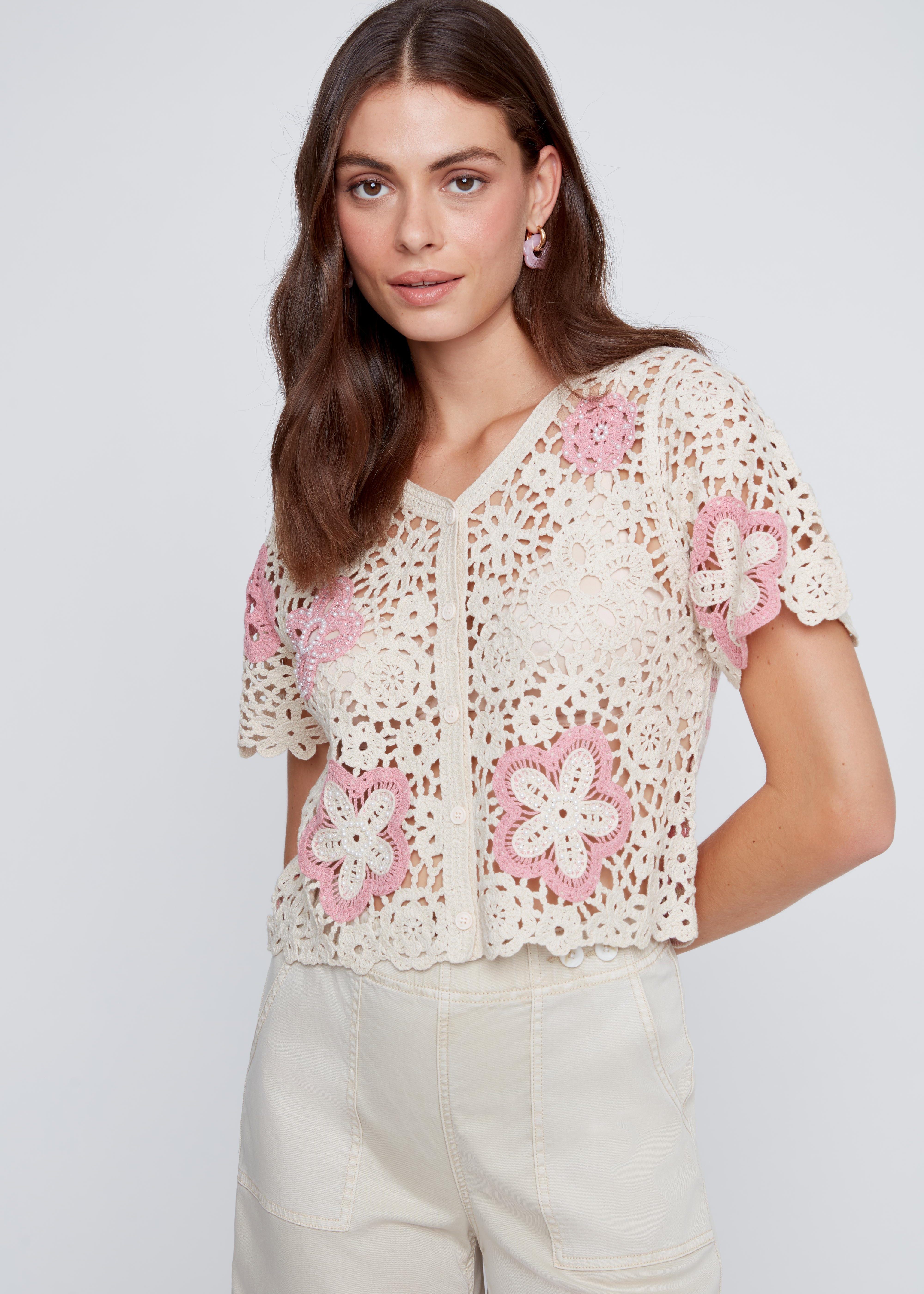 Chandail en crochet écru avec fleurs ajourées et perles à l’avant, dos à motifs de cercles et lignes rose et écru.