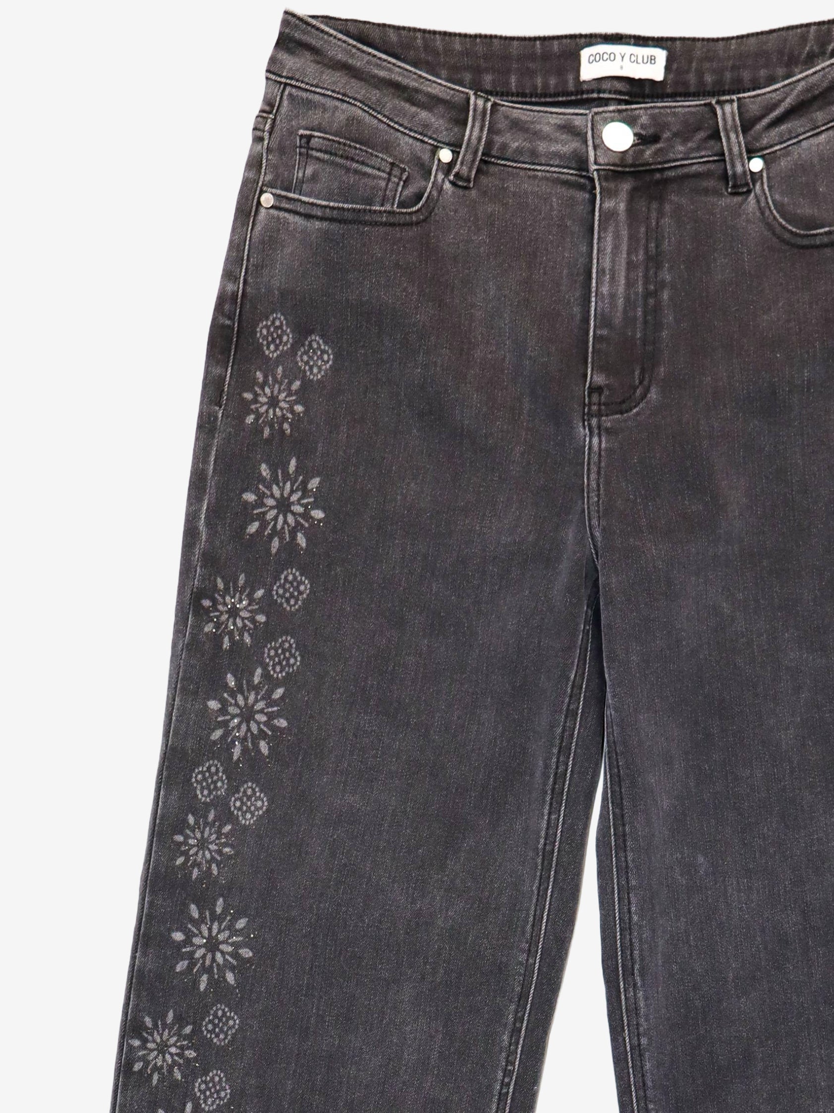 Gros plan des motifs floraux ton sur ton sur le jean noir CYC