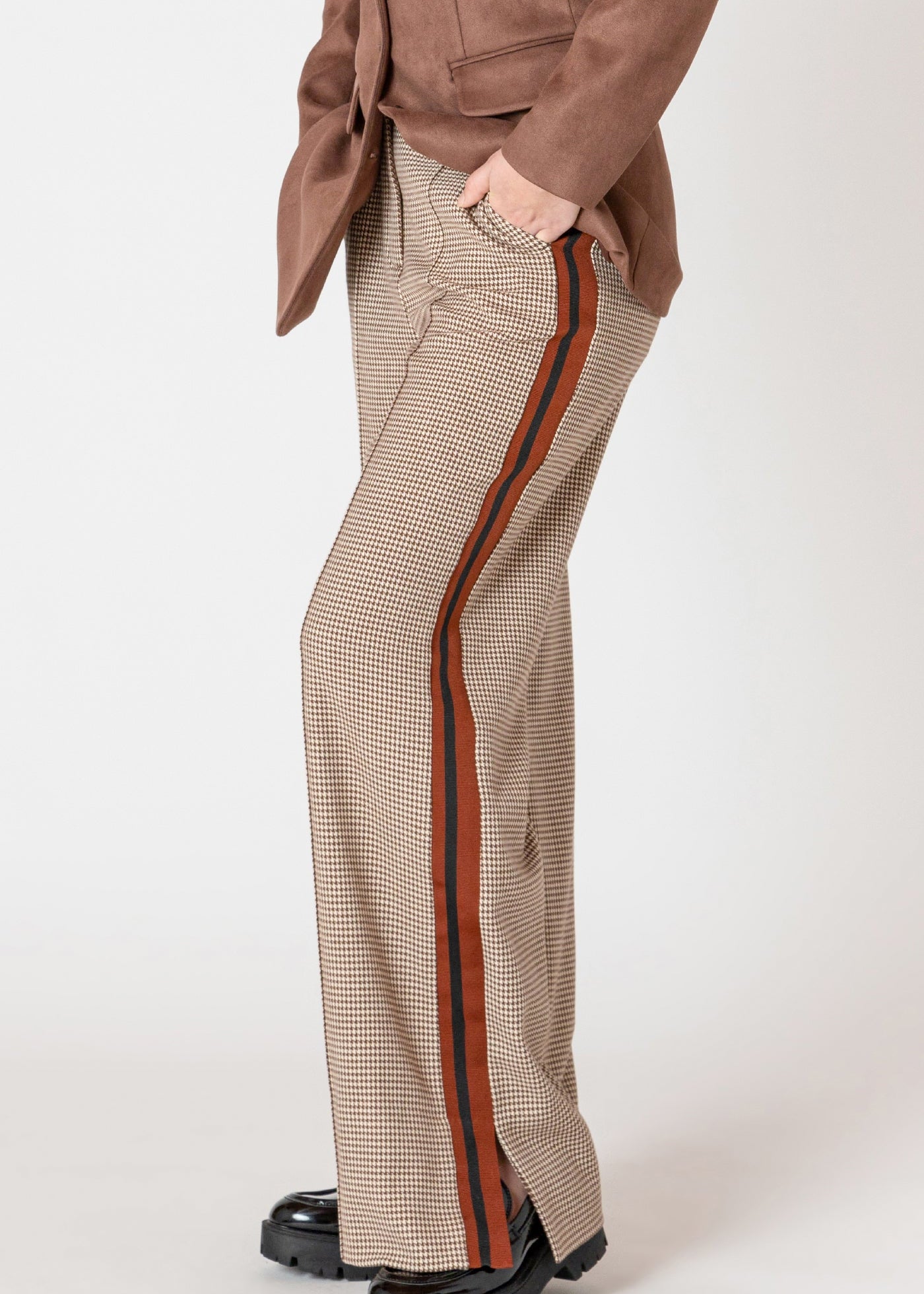 Pantalon en tricot extensible Black Tape, motif micro pied de poule brun et beige, avec une bande rouge et noire sur la jambe.