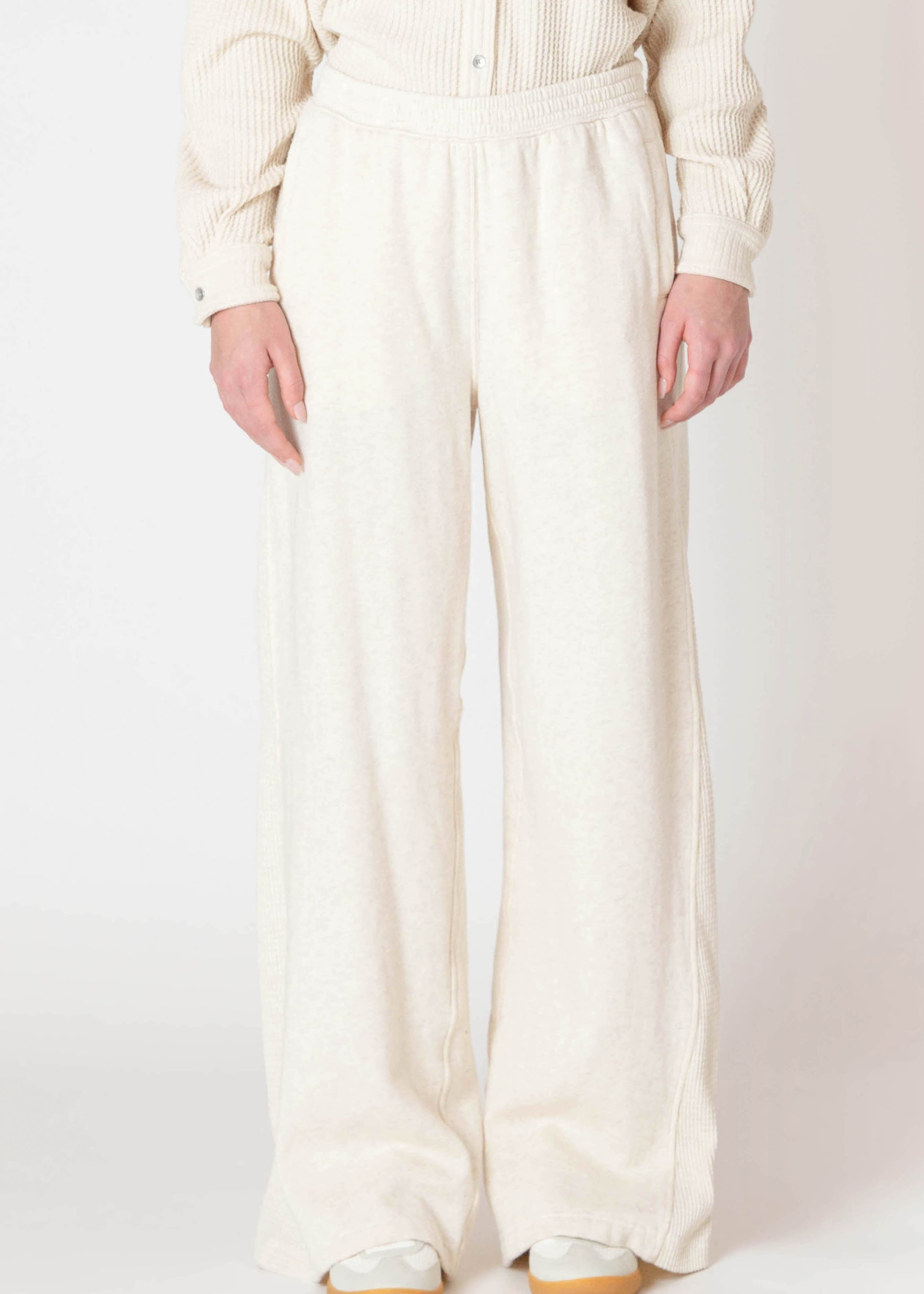 Jogging évasé de la compagnie Room 34, de couleur crème en coton outé, avec un détail de tissu texturé sur le côté de la jambe.