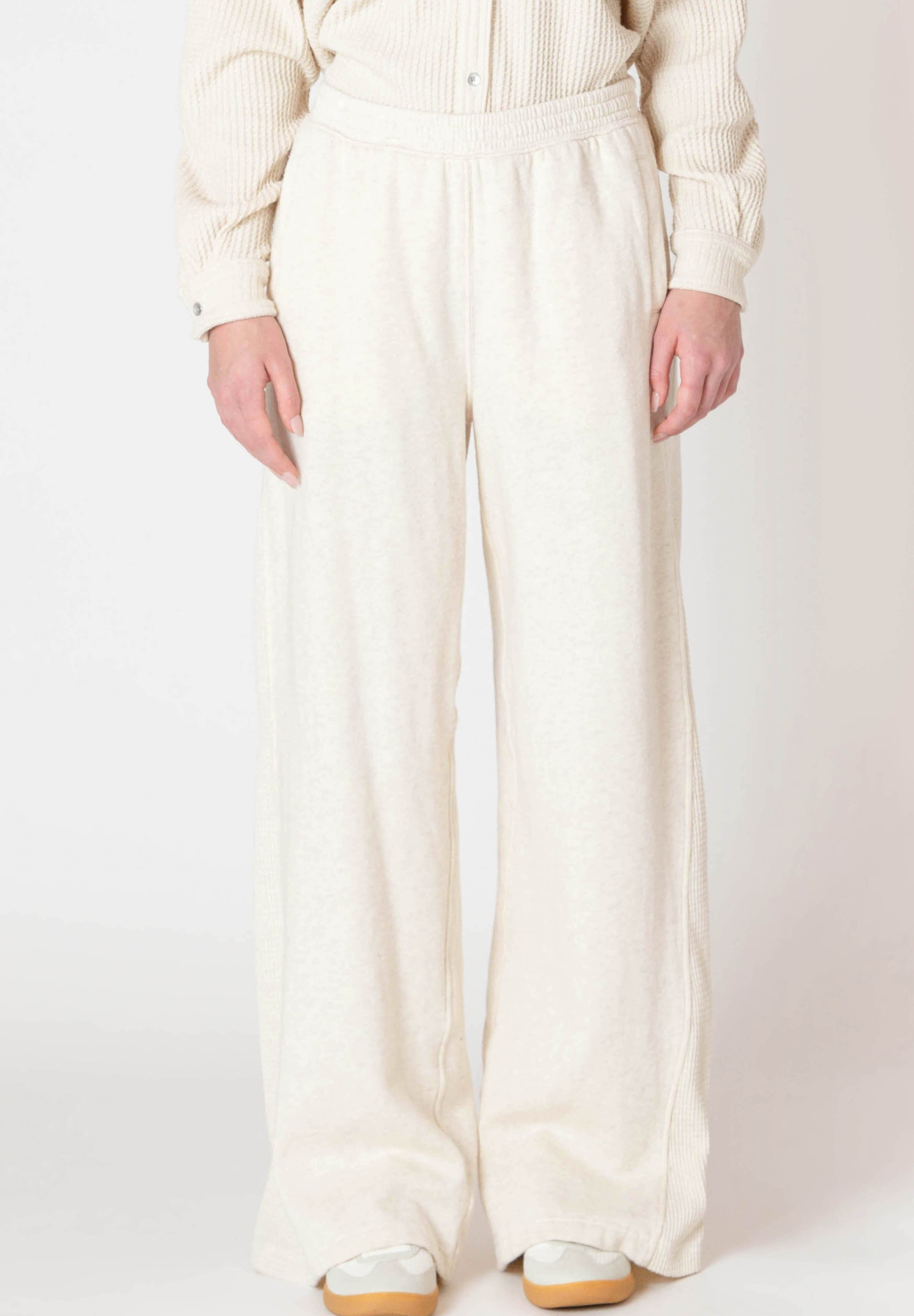 Jogging évasé de la compagnie Room 34, de couleur crème en coton outé, avec un détail de tissu texturé sur le côté de la jambe.