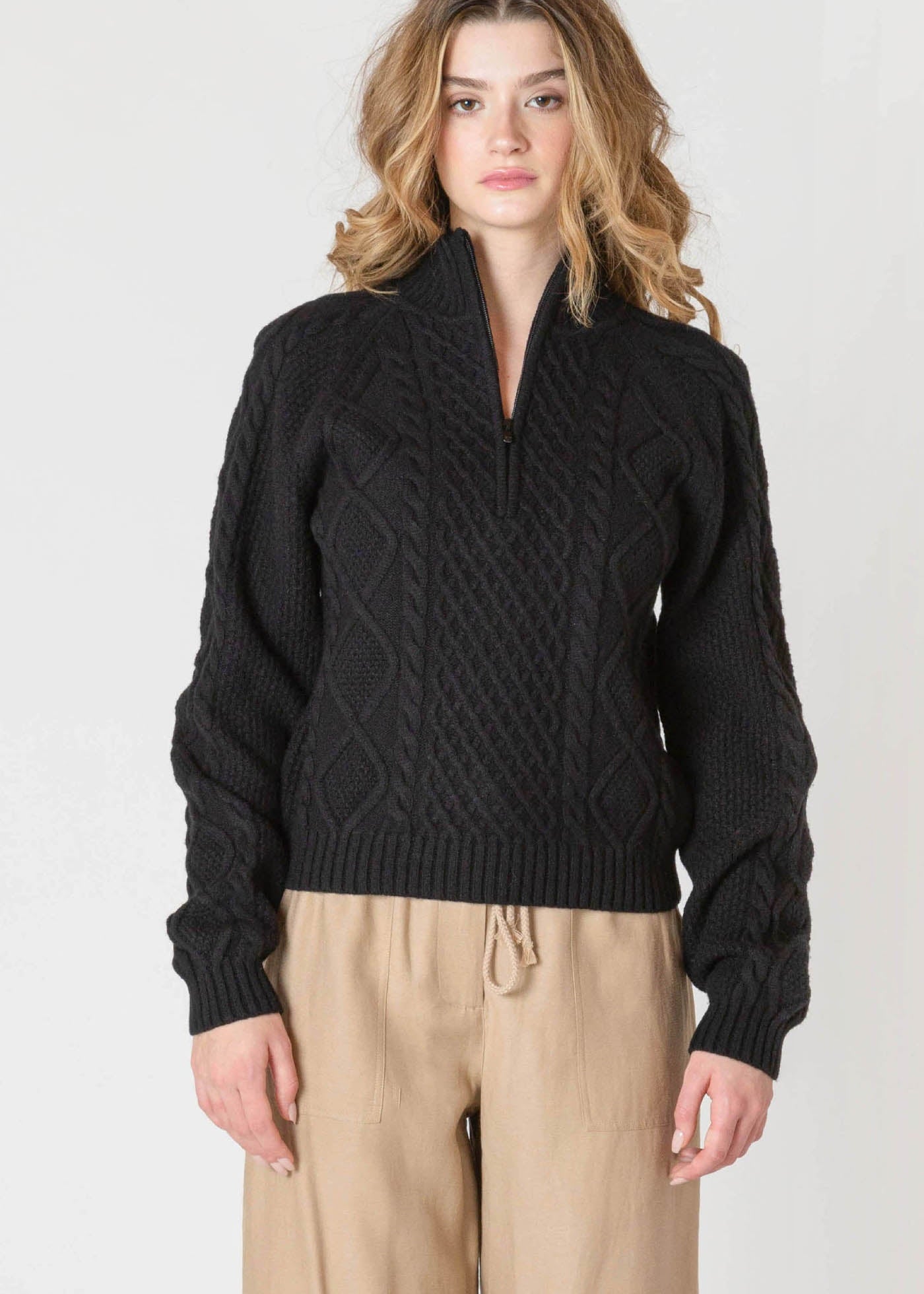 "Chandail en tricot noir uni, doté d'un col montant et d'une demi-fermeture éclair sur le devant. Matière 100% polyester pour une bonne tenue. Marque Room 34."