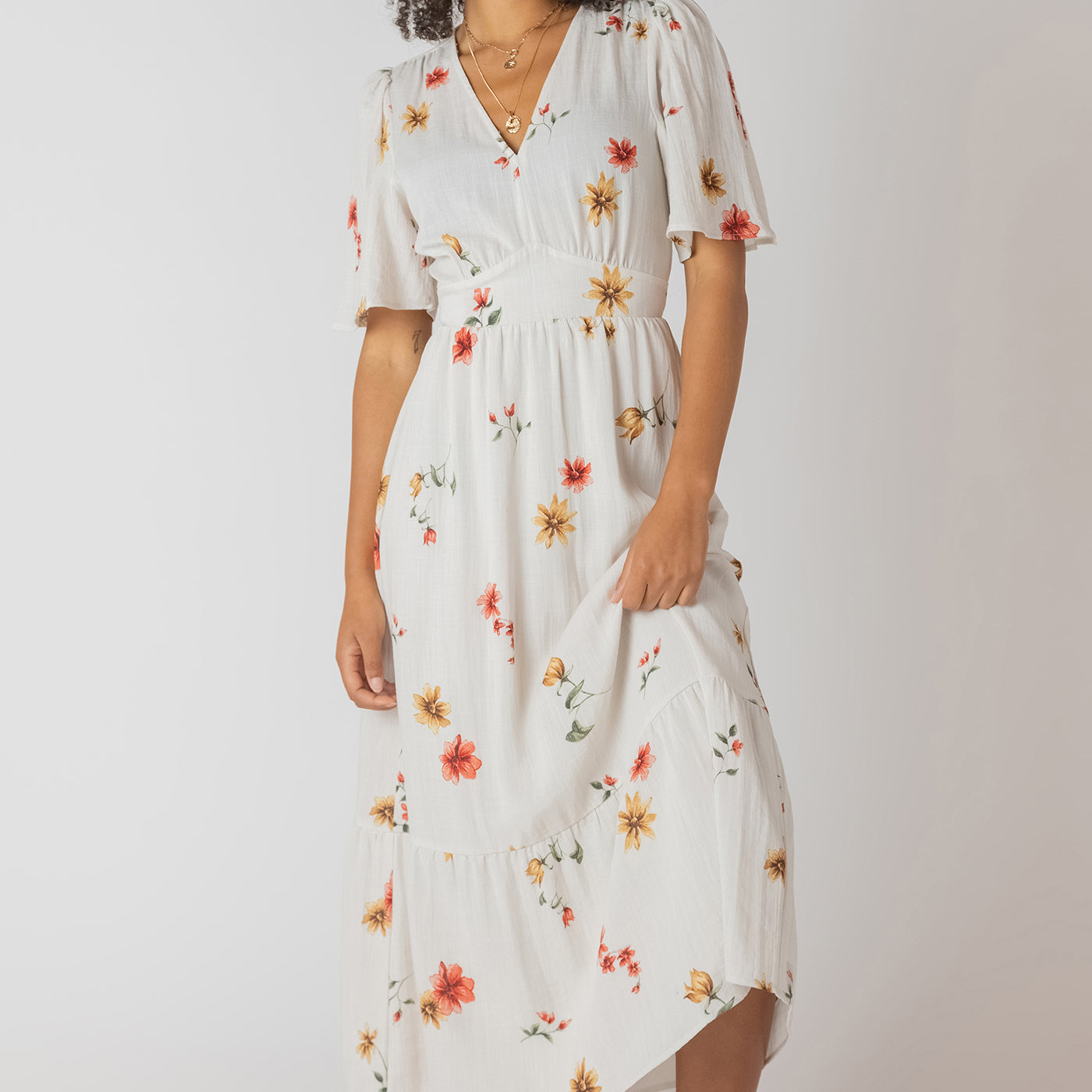 Robe longue à imprimé floral multicolore, col en V et dos nu, tissu souple en polyester et élasthanne, style féminin et léger.