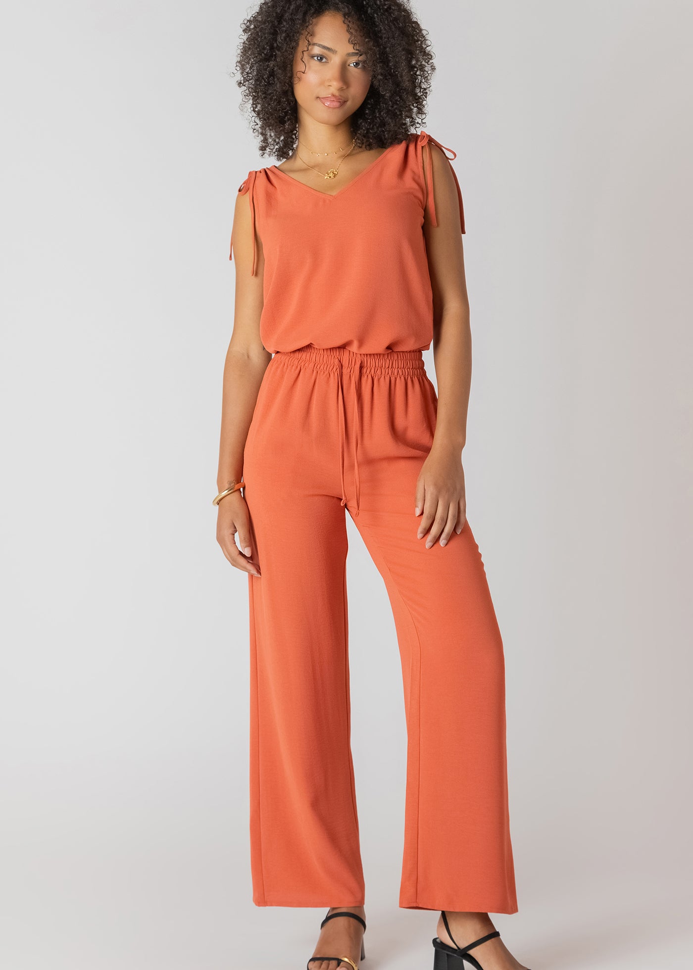 Pantalon fluide large à taille élastique, couleur cuivre, tissu infroissable en polyester, coupe confortable et élégante.