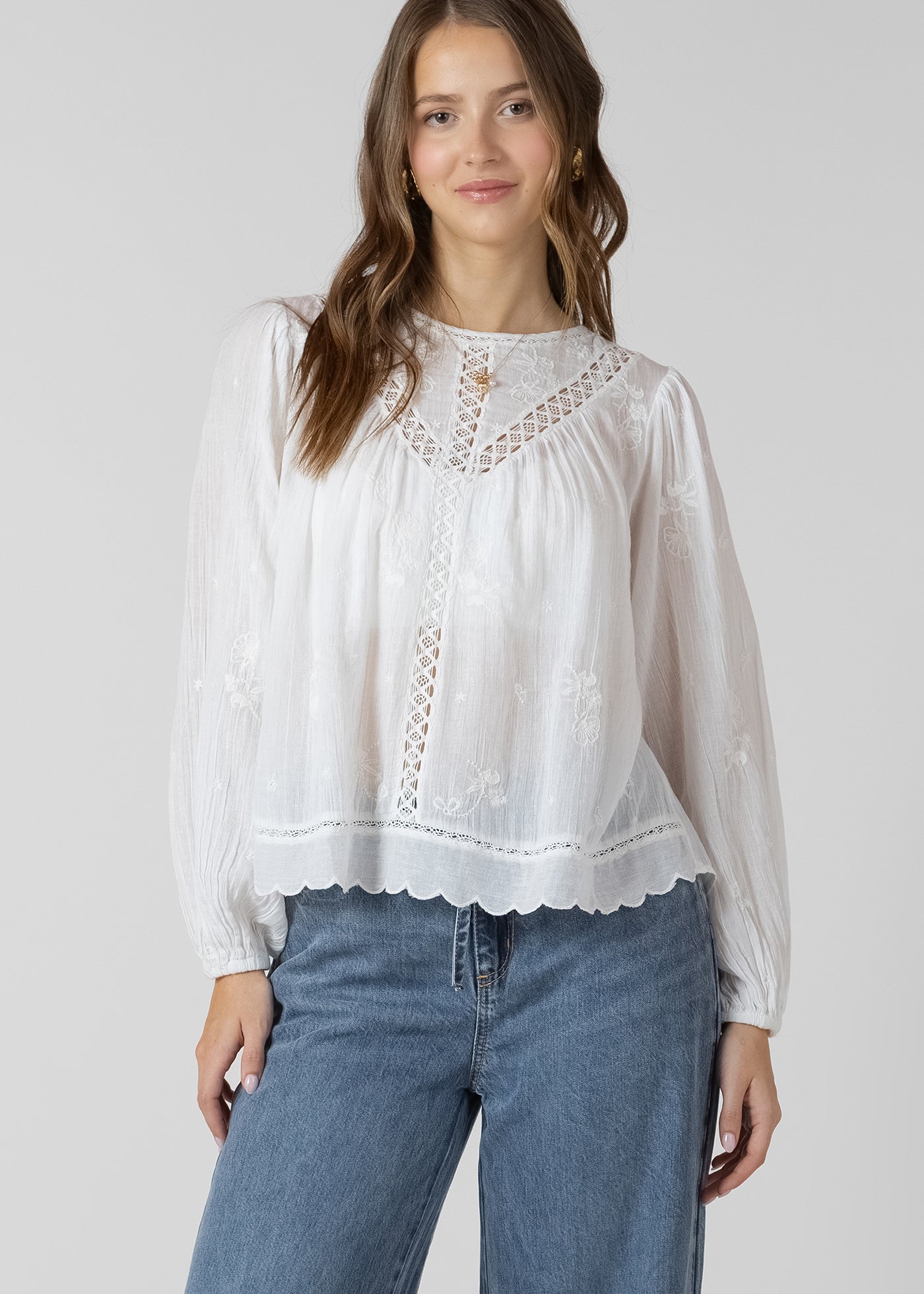 Blouse avec broderies de fleurs et détails de dentelle, manches avec élastique, style féminin et estival.