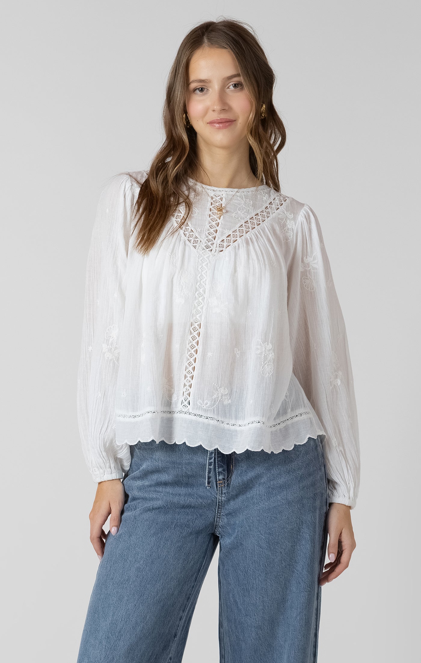 Blouse avec broderies de fleurs et détails de dentelle, manches avec élastique, style féminin et estival.