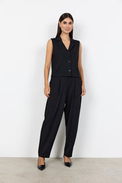 Veste noire courte sans manches portée avec un pantalon habillé