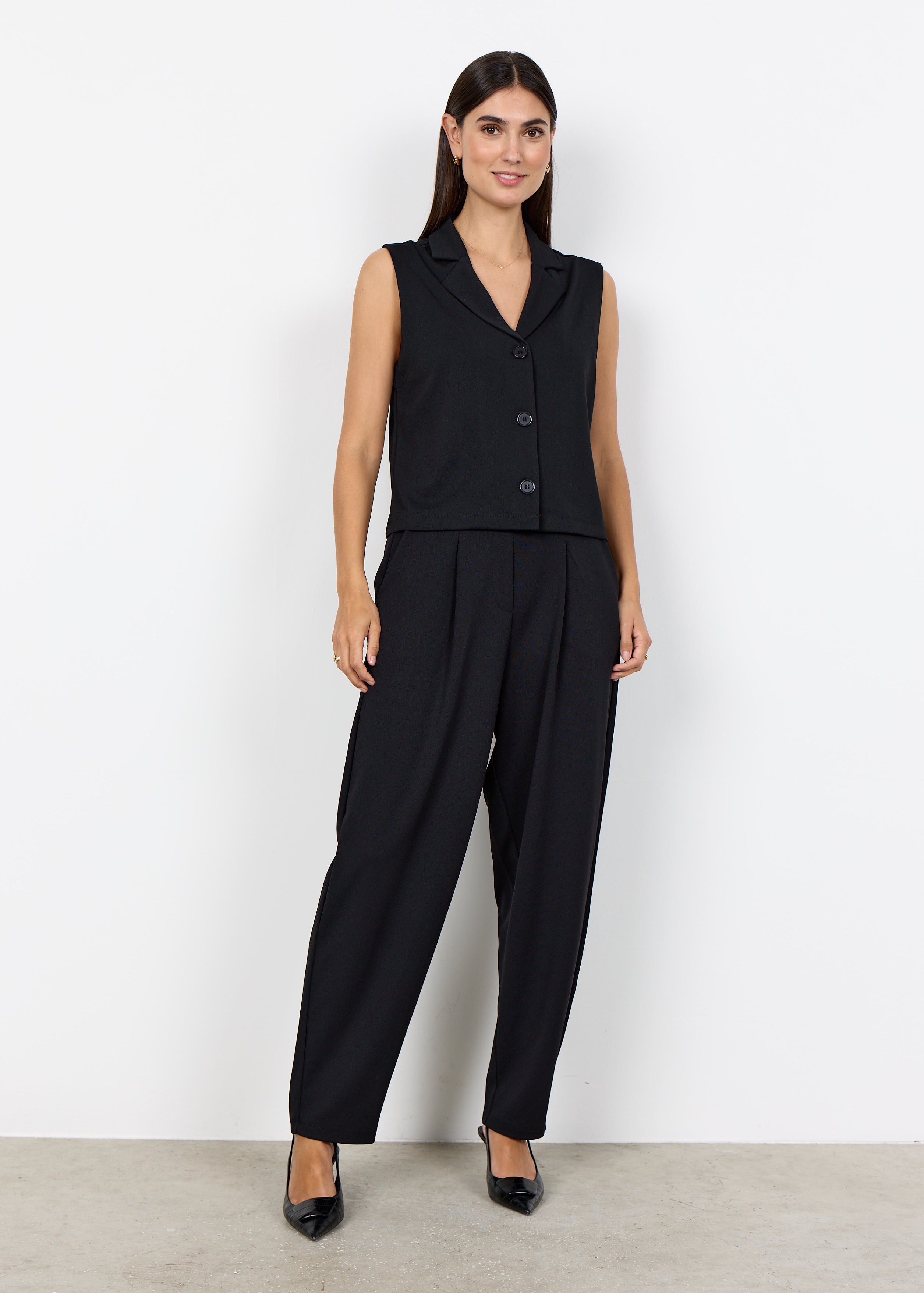 Veste noire courte sans manches portée avec un pantalon habillé