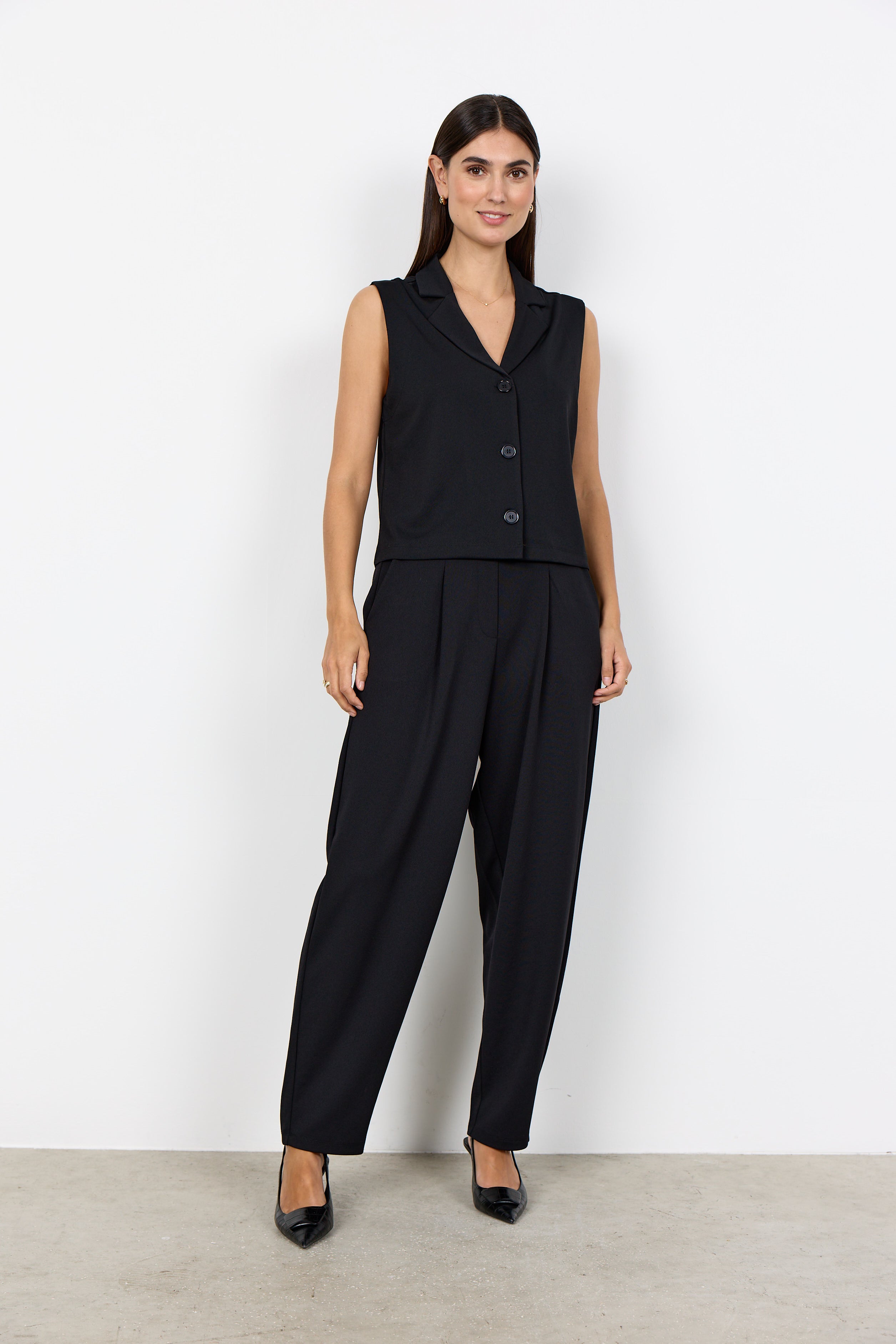 Veste noire courte sans manches portée avec un pantalon habillé