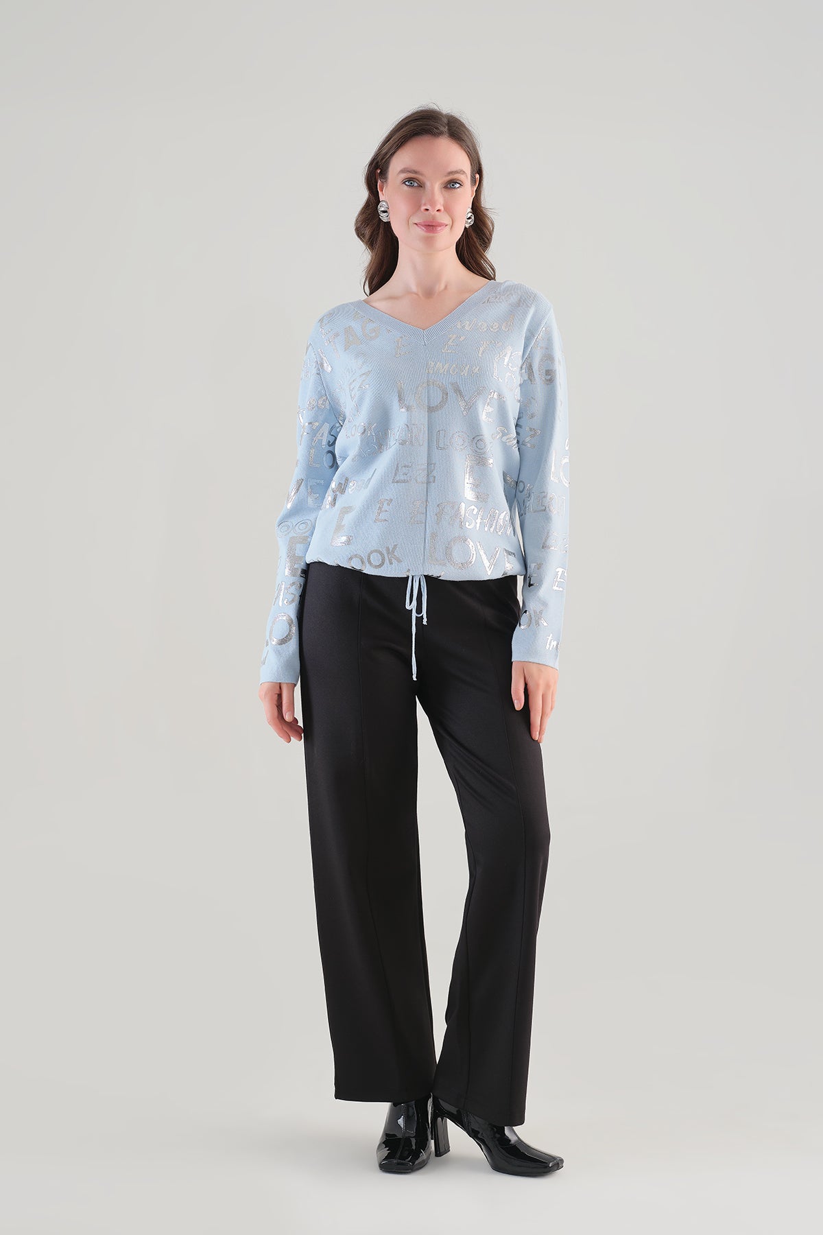 Femme portant le chandail bleu Tricotto 96111 à col V, motif lettré argenté et cordon ajustable, vue de face