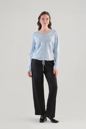 Femme portant le chandail bleu Tricotto 96111 à col V, motif lettré argenté et cordon ajustable, vue de face