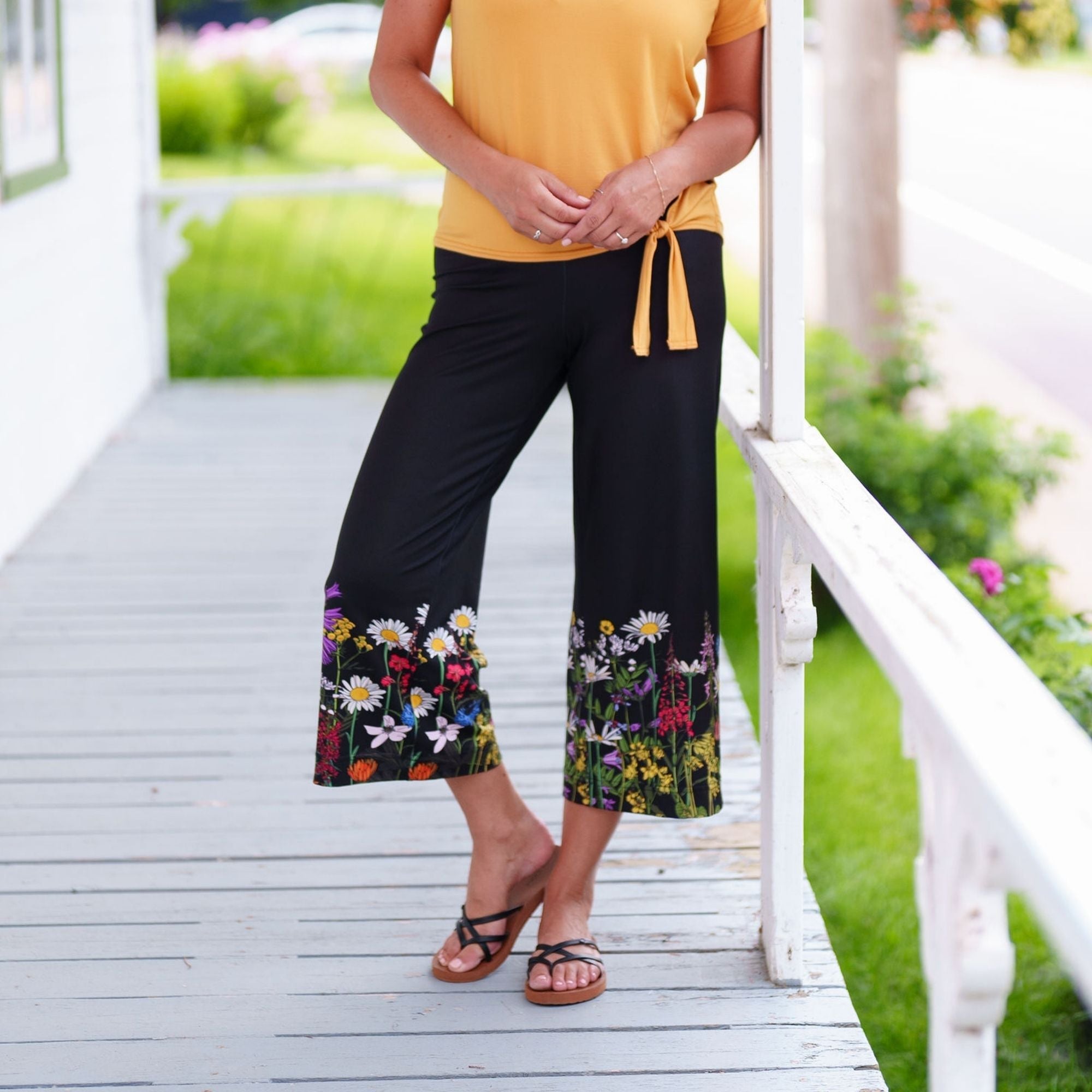 "Pantalon gaucho noir à jambes larges de la marque Rien ne se perd, avec une bordure florale colorée au bas des jambes, présenté sur un fond neutre."