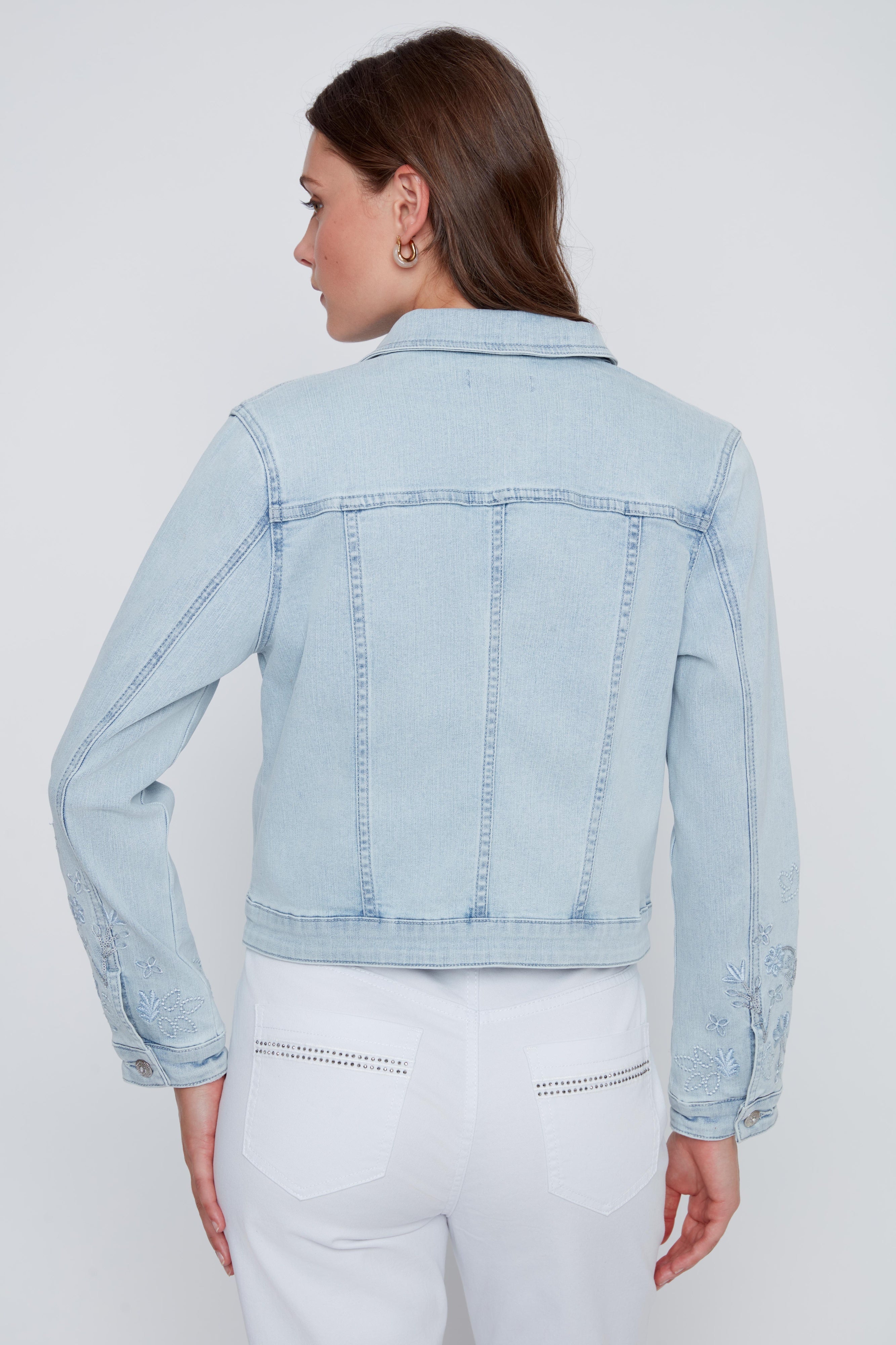 Veste de jeans pour femme en bleu denim pâle avec broderies florales à paillettes, détails brillants aux poches et boutons de fermeture à l’avant.