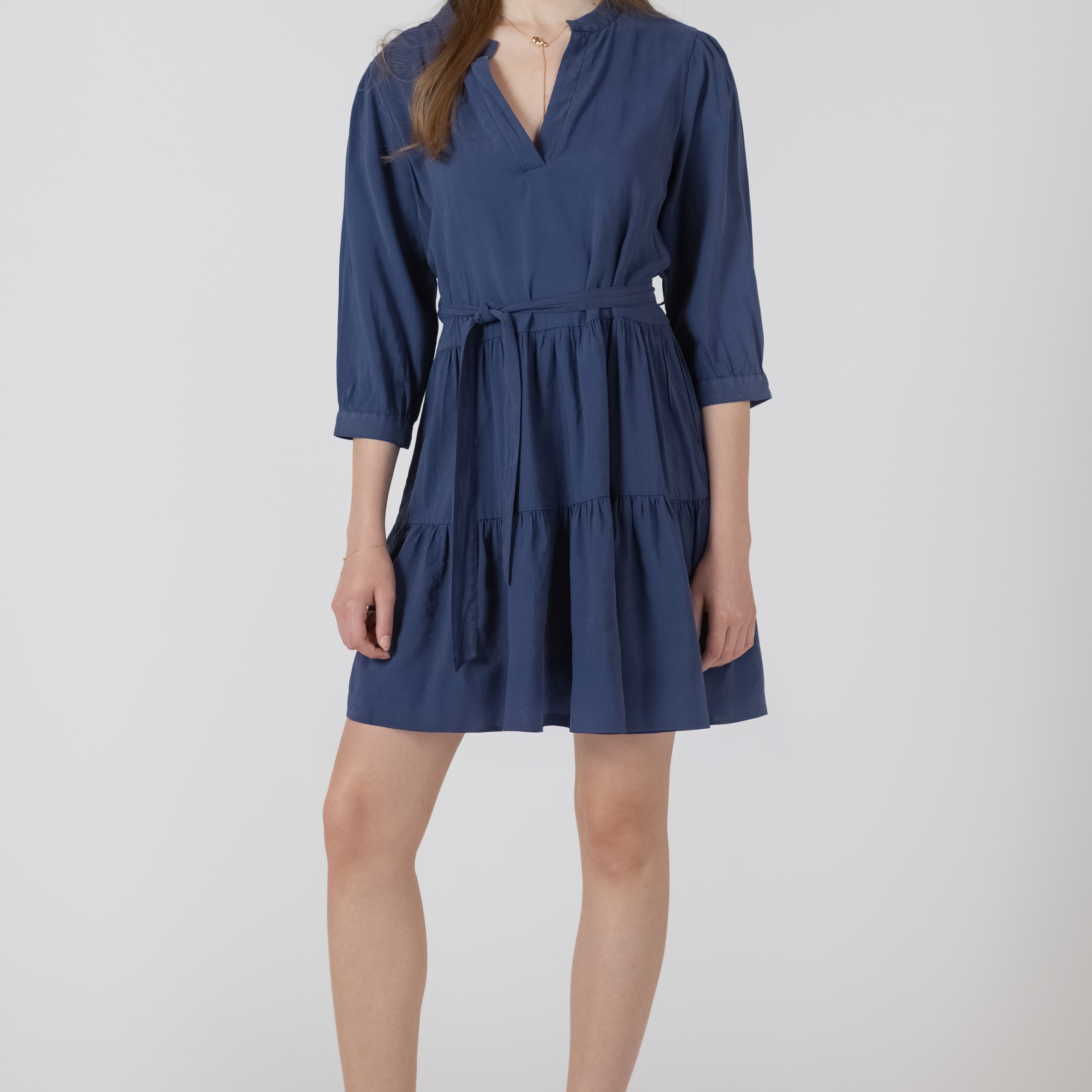 Robe courte pour femme style paysanne, col V, manches trois quarts, ceinture amovible à la taille, tissu en tencel bleu denim effet légèrement délavé, allure estivale et confortable.