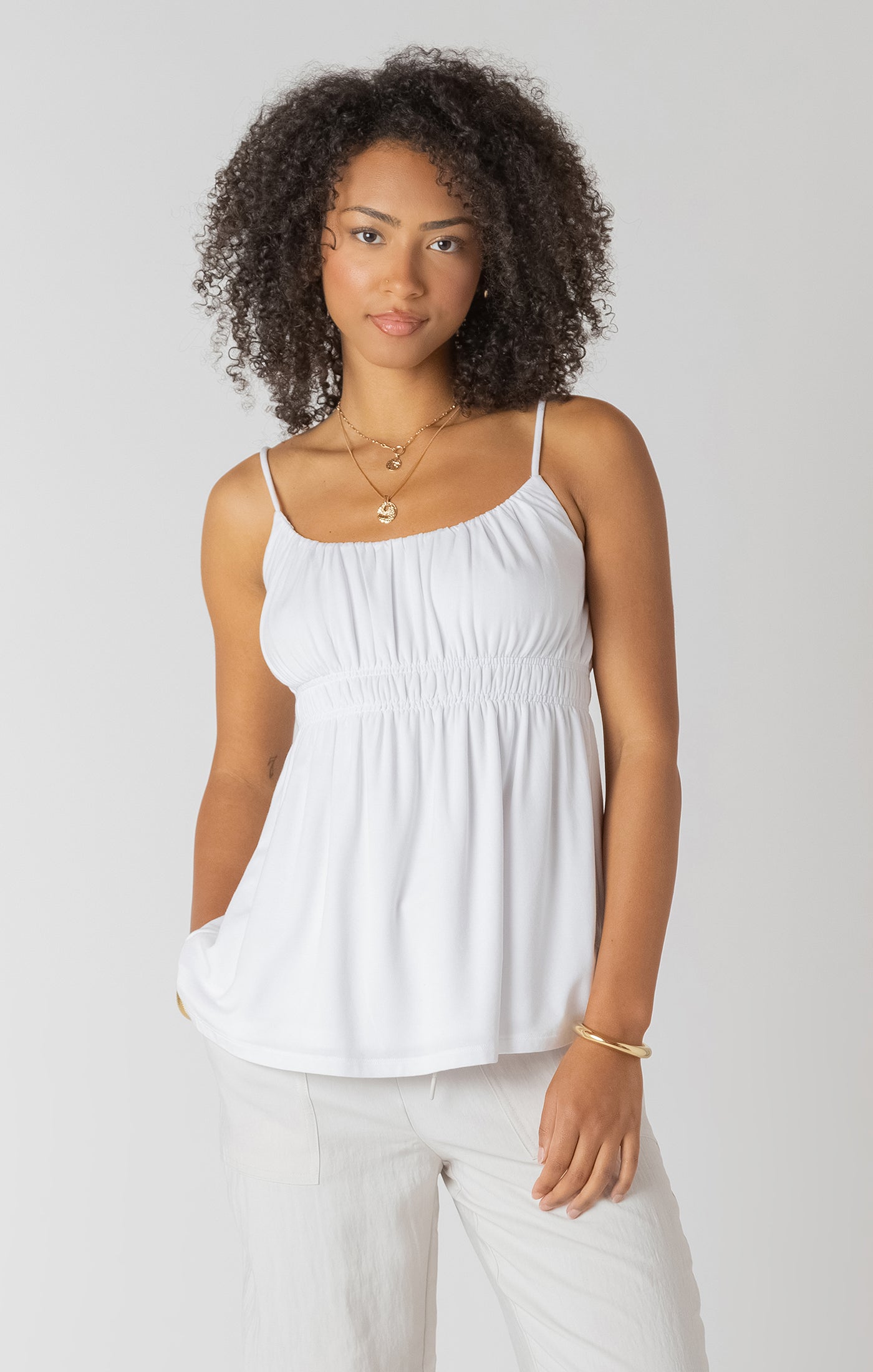 Camisole blanche pour femme à bretelles spaghetti, coupe ceintrée au buste, tissu souple et confortable.