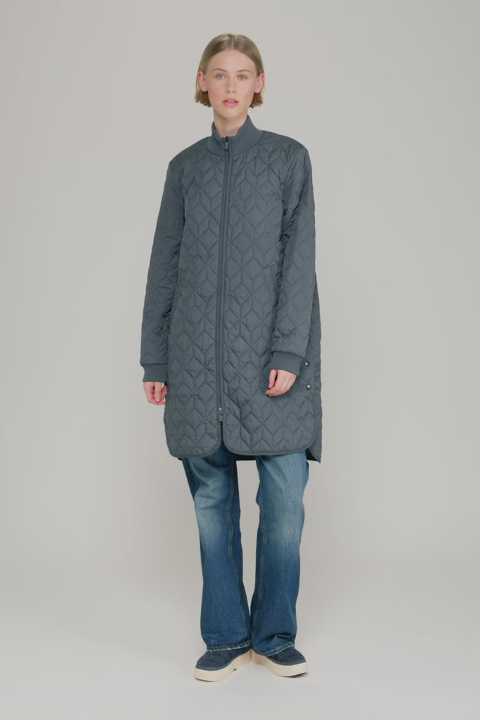 Manteau matelassé long ILSE JACOBSEN HORNBÆK de couleur unie, avec col montant côtelé, poches latérales et fermeture éclair bidirectionnelle.