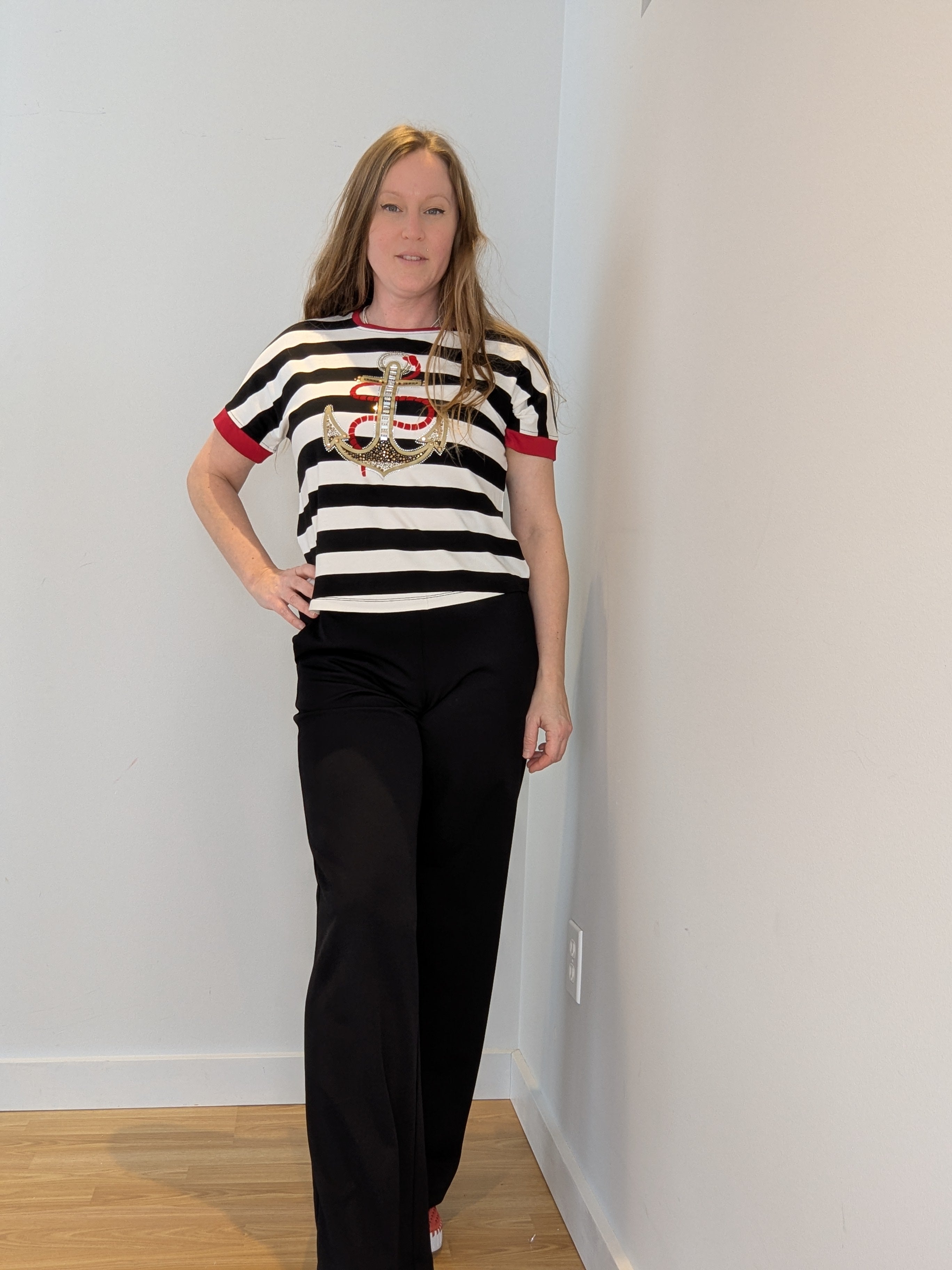 Chandail à manches courtes pour femme rayé noir et ivoire, avec détails rouges, appliqué d’ancre de bateau dorée avec strass multicolores et touche de velours rouge, style élégant et confortable.